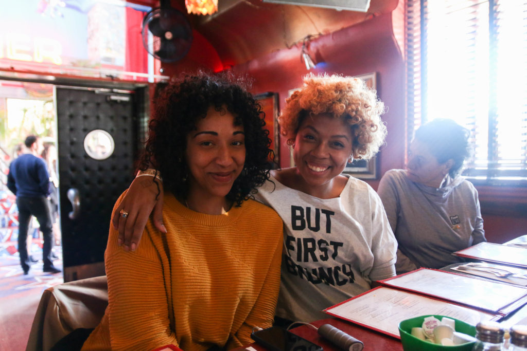Two girls in a restaurant smiling at the camera.