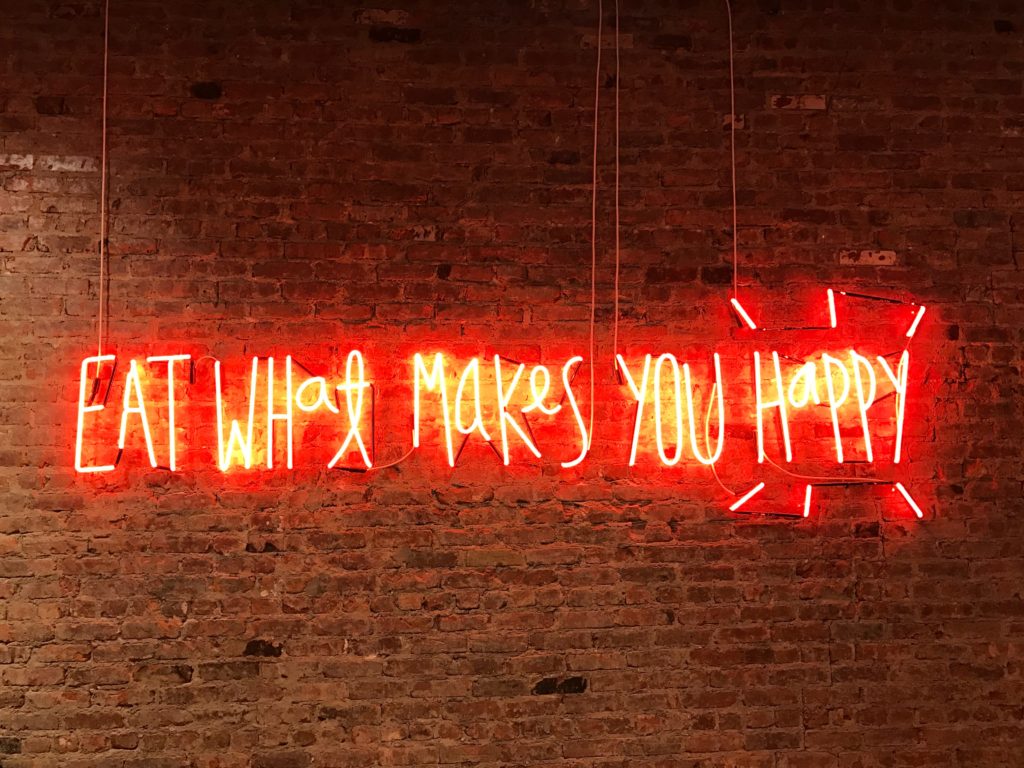 A neon sign that reads "Eat What Makes You Happy"